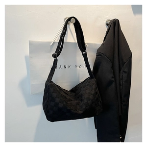 Détail du sac hobo noir à motif damier avec bandoulière réglable sur fond minimaliste