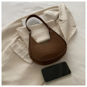 Detail of hobo bag with brown crocodile pattern and gold buckle in lifestyle setting