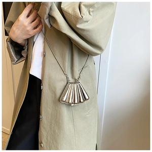Fashionable shell-shaped silver mini crossbody bag with metal chain on trench coat
