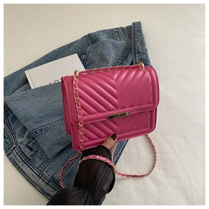 Close-up of pink quilted crossbody bag with chevron pattern and gold chain strap