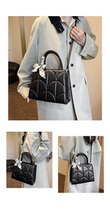 Détail d'un sac à main noir matelassé avec foulard en soie et bandoulière amovible