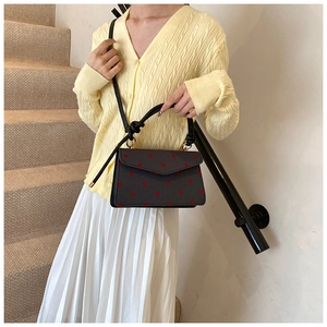 Details einer Vintage Umhängetasche aus schwarzem Leder mit roten Punkten und Knotengriff