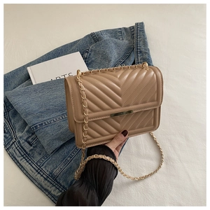 Detail of beige quilted shoulder bag with V-shaped stitching and golden chain strap