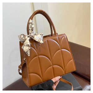 Gros plan du sac à main marron avec surpiqûres en éventail et foulard en soie décoratif