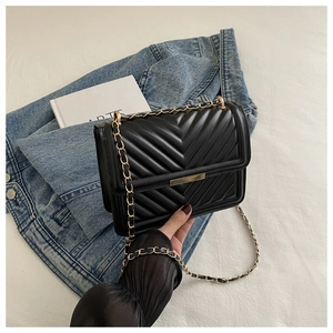 Detailed view of black quilted leather shoulder bag with gold metal clasp and chain strap