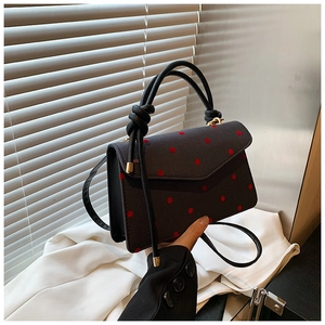 Detailaufnahme der schwarzen gepunkteten Handtasche mit Knotengriff und Riemen