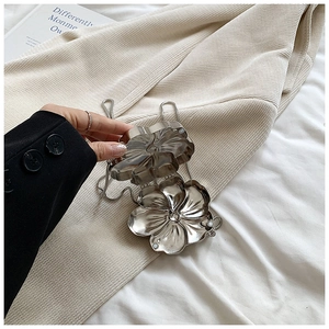 Detailed view of silver flower-shaped clutch bag with metal chain strap and magnetic closure