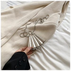 Mini silver shell-shaped chain bag with metallic mirror finish on a corduroy background