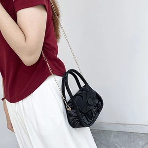 Minimalist black marble textured crossbody bag with gold chain strap on woman