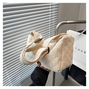 Gros plan du sac bandoulière tressé crème avec larges lanières en cuir et boucle noire