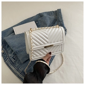 Detail of white V-quilted faux leather crossbody bag with gold chain and flap closure