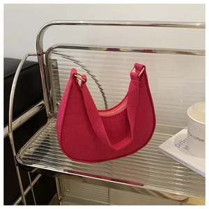 Detail of rose red felt shoulder bag with crescent shape and gold metal ring hardware