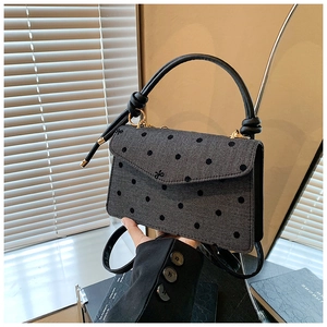 Detail einer Handtasche aus grauem Fischgrätgewebe mit schwarzen Punkten und Schleife