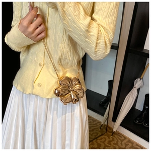 Detail of creative golden flower crossbody bag with chain strap on model's outfit