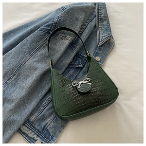 Détail du sac à bandoulière vert motif crocodile avec un nœud en métal argenté