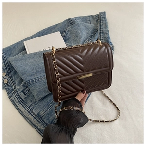 Detail of dark brown V-quilted faux leather bag with elegant gold chain strap and metal clasp
