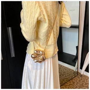 Detailed view of the mirror-finished gold flower bag with a delicate metal chain strap