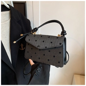 Detailaufnahme der grauen Umhängetasche mit Fischgrätenmuster und schwarzen Polka Dots