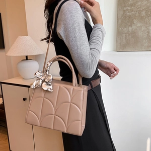 Sac à main beige matelassé élégant avec foulard en soie dans un cadre de vie moderne