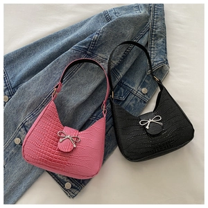 Vue détaillée de la texture crocodile et des boucles en nœud argenté sur sacs rose et noir