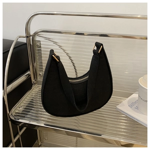 Detail of a black moon-shaped hobo bag with a gold zipper and fine textured fabric