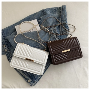 Detail of V-quilted faux leather crossbody bags in white and brown with gold chain straps