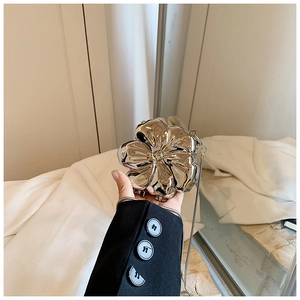 Detail of silver flower clutch bag with a mirror finish and metal chain shoulder strap