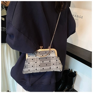Detail of a vintage kiss-lock crossbody bag with grey plaid and black mesh overlay