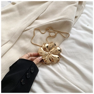 Detailed view of a gold flower hard shell clutch bag with a metallic snake chain