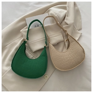 Detailed close-up of crescent underarm bags with crocodile embossed texture in green and cream