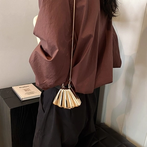 Chic gold shell-shaped mini clutch with metal chain strap shown on a modern model