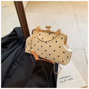 Detail of white polka dot clutch with vintage gold clasp and elegant chain strap