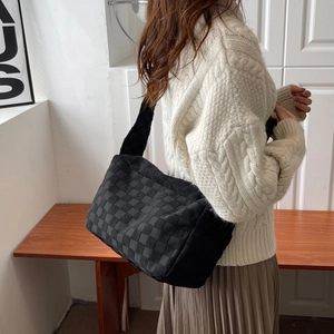 Sac hobo tissé noir minimaliste avec large bandoulière porté par une femme