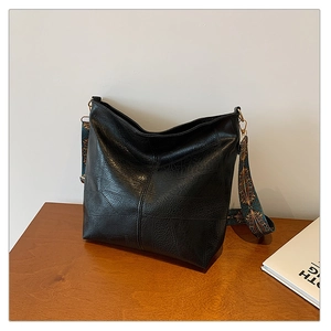 Close-up of black retro textured tote bag with wide geometric pattern woven shoulder strap