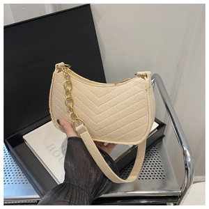 Detail of beige quilted hobo bag with V-shaped texture and gold chain strap
