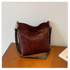 Detail of burgundy leather tote featuring geometric stitching and bohemian embroidered strap