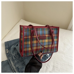 Macro detail of the multi-colored plaid tote bag with red leather straps and trims