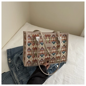 Detailed close-up of woven geometric jacquard tote bag with leather handles on denim