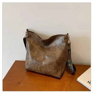 Detail of retro brown tote bag featuring lychee texture and ethnic geometric shoulder strap