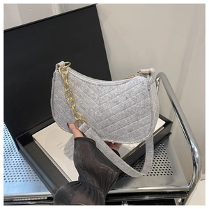 Detail of grey felt shoulder bag featuring V-shaped quilting and gold metal chain strap