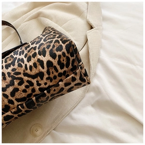Detailed close-up of leopard print shoulder bag on a beige corduroy textured jacket