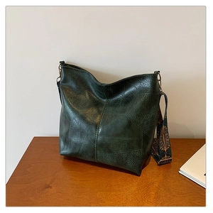 Detail of dark green vintage tote bag featuring a colorful geometric wide shoulder strap