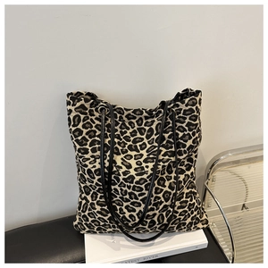 Detalle de bolso tote grande de lona con estampado de leopardo y correas negras finas con ojales