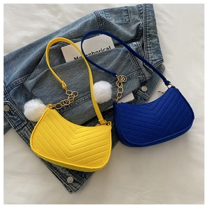 Detailed view of yellow and blue quilted crescent bags with plush pompoms and gold chains