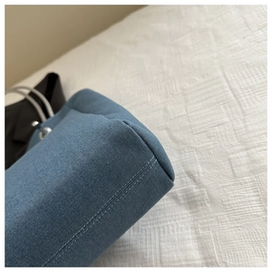 Gros plan d'un sac cabas en denim bleu montrant les coutures doubles de qualité sur le coin