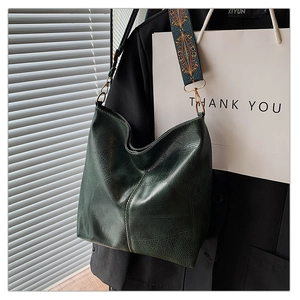 Detail of dark green tote bag featuring lychee texture leather and geometric woven strap