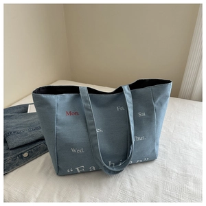 Macro detail of blue denim tote bag featuring fashion text print and spacious interior