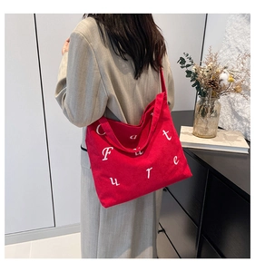Gros plan détaillé d'un sac cabas en velours côtelé rouge avec broderie blanche