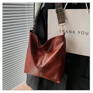 Detail of vintage brown leather tote bag featuring a colorful ethnic style wide strap