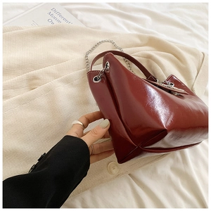 Gros plan du sac fourre-tout bordeaux en cuir brillant avec bandoulière chaîne argent
